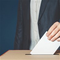Image of a man placing a voting paper in a ballot box.