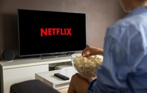 Woman with popcorn watching a TV that has the Netflix logo displayed on