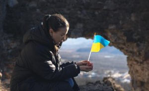 young woman holding Ukrainian flag in warzone