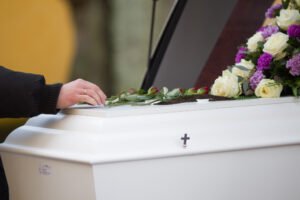 Person placing a flower on a coffin