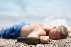 man passed out on a beach drunk