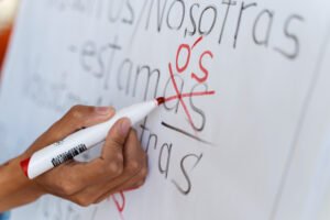 hand correcting Spanish verbs on a whiteboard