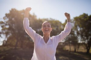 happy woman with arms flung up in air