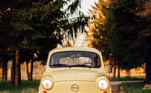 Old Fiat 500 in yellow on a tree lined road