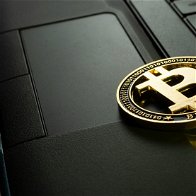 Bitcoin lying on top of a laptop