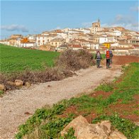 View of the Camino de Santiago with 2 people walking towards a town