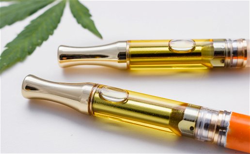 2 vape pens with liquid in them hemp leaf in background
