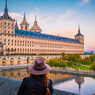 Astonishing UNESCO World Heritage site in incredible Spanish city 'tourists don't know about' reopens after €6.5m revamp.  A young woman wearing a hat watching a beautiful sunset in front of the stunning water pond at Frailes Garden at San Lorenzo de El Escorial monastery near Madrid, Spain's capital.