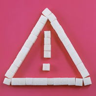 Warning sign made of sugar cubes on a pink background, symbolising food safety alerts