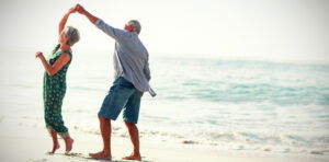 Senior couple dancing at beach on sunny day. Credit: vectorfusionart, Shutterstock.
