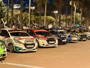 A row of rally cars arrive at the podiums. 