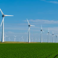Wind turbines in a green grassy field with clear blue skies, an aid in climate change