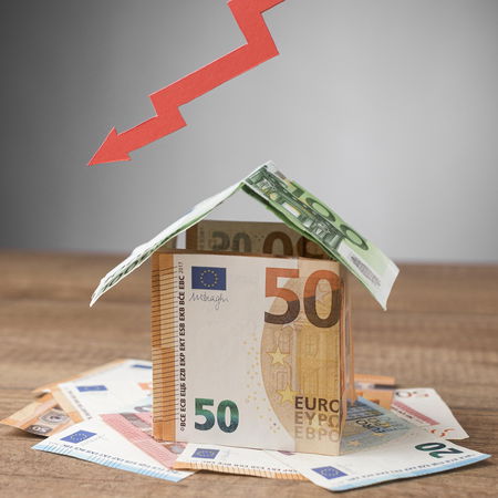 Euro banknotes shaped like a house with a downward arrow, symbolising Spain’s rising housing costs.