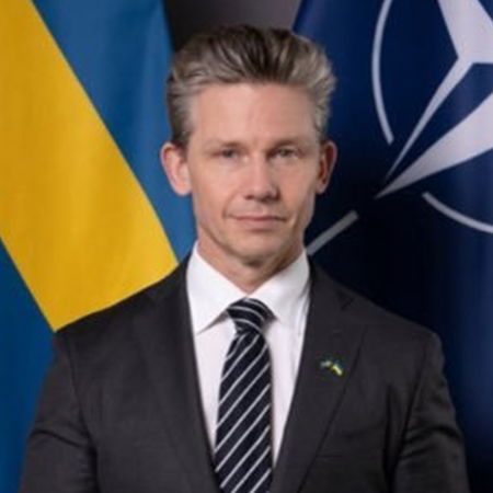 Pål Jonson standing in front of the Swedish and NATO flags during a security briefing.