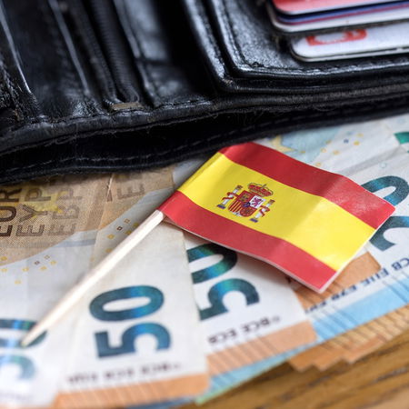 Wallet with euro banknotes and a small Spanish flag, symbolising cash controls in Spain.