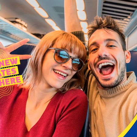 Two young travellers smiling on a train during a DiscoverEU journey organised by the European Commission.