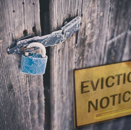 Padlocked wooden door with an eviction notice, symbolising housing insecurity and eviction proceedings in Spain.