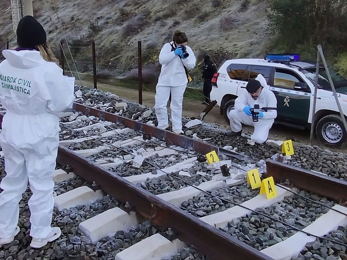 Investigators look at broken section of track and burn marks.